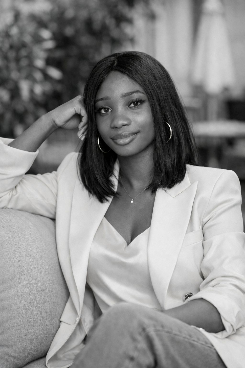 Chioma Iheme, founder of Dear Black Women in Italy in a black and white photo, sits relaxed and confident. Her hair is in a shoulder-length bob as she rocks a camisole and a blazer over it.